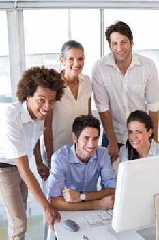 Attractive business people smiling at the camera whilst working on a computer