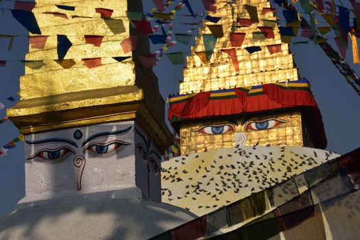 Boudhanath Stupa. Golden spire and all seeing Buddha eyes on top a giant white hemisphere. Smaller stupa in foreground. Kathmandu, Nepal