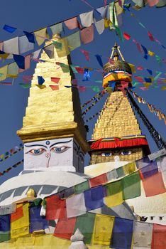 Boudhanath Stupa. Golden spire and all seeing Buddha eyes on top a giant white hemisphere. Smaller stupa in foreground. Kathmandu, Nepal