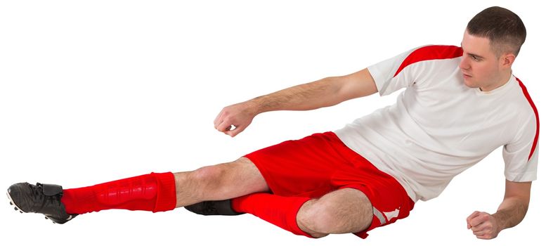 Fit football player playing and kicking on white background