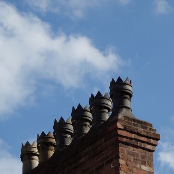 Row of decorative victorian chimneypots with blue sky in background