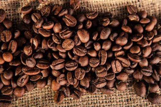 close up of coffee beans scattered on jute. point of view from below