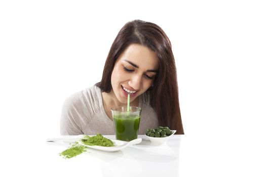 Beautiful smiling girl drinking green drink. Spirulina, chlorella and wheatgrass. Healthy lifestyle, detox.