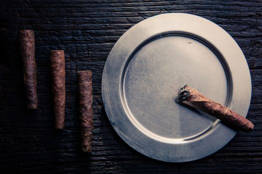 geometric composition of cigars end ashtray. the cigar is lit