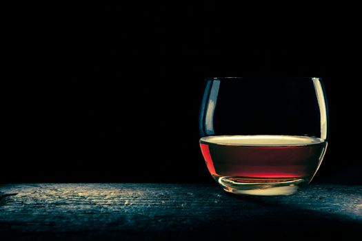 rounded glass of bourbon in shadows, minimal composition