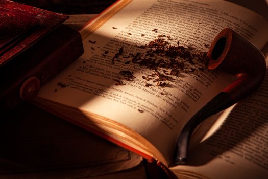 detail of writer studio. an opened book with a pipe on it, some tobacco scattered on the page, a notebook on the left.low light and shadows.warmth ambient