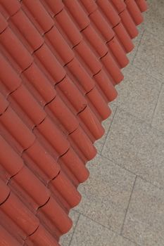Closeup detail of a Slanted awning made of ochre colored terracota tiles is seen with a cement mosaic floor in backround