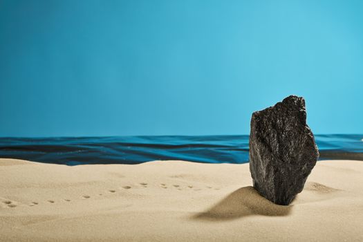 rock on a summer beach with footprints