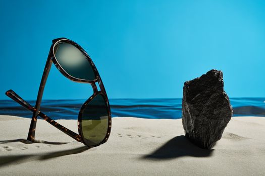 sunglasses and rock on a summer beach in front of a placid ocean