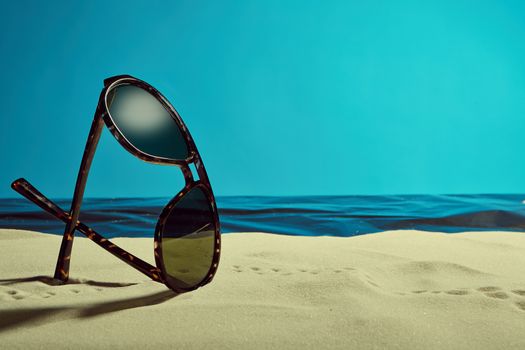 sunglasses on summer beach with little footprints