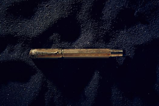 golden pen on dark sand