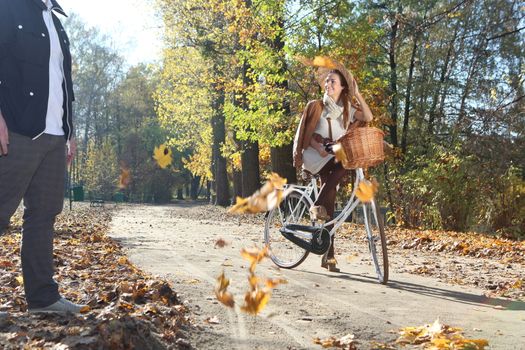 girl on a bicycle in a park alley background color of autumn leaves