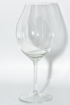 Broken clear wineglass with sharp glass fragments inside on white background