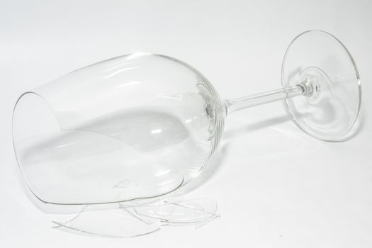 Shattered broken-down wine glass with sharp shards lying on white background