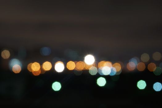 Orange, green and blue bokeh glitter in the night background.