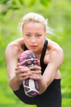 Young caucasian lady is practicing head to the knee yoga pose in the nature.