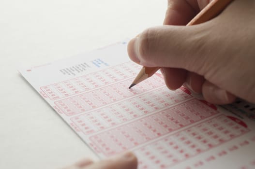 Close-up of a person marking number on lottery ticket with pen