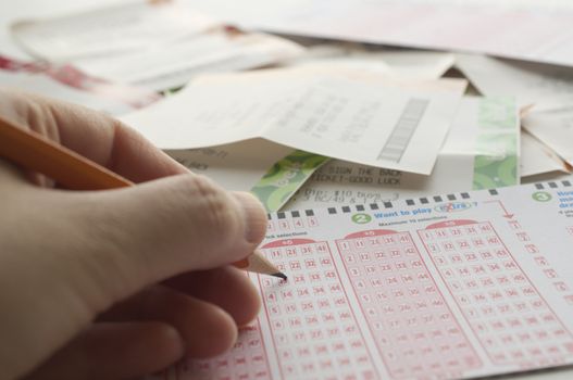 Close-up of a person marking number on lottery ticket with lottery ticket background