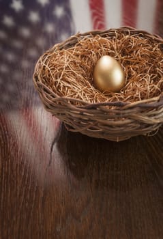 Golden Egg in Nest with American Flag Reflection on Wooden Table.