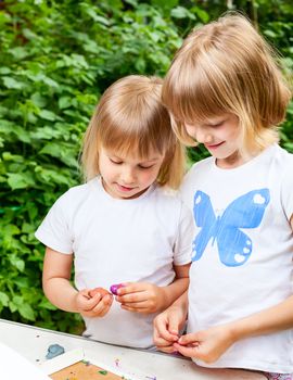 Two little girls are playing with modelling clay outdoor