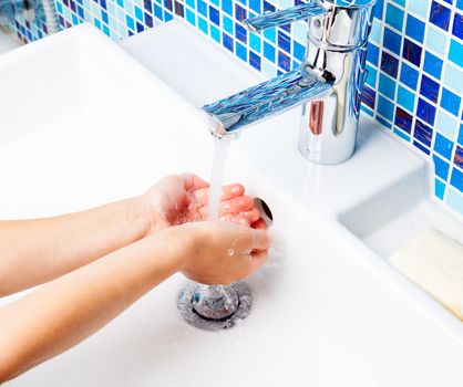 Girl washing her hands in bathroom sink