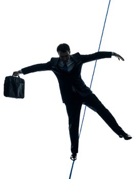 one caucasian Businessman tightrope walker in silhouette studio isolated on white background