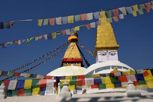 Boudhanath Stupa. Golden spire and all seeing Buddha eyes on top a giant white hemisphere. Smaller stupa in foreground. Kathmandu, Nepal