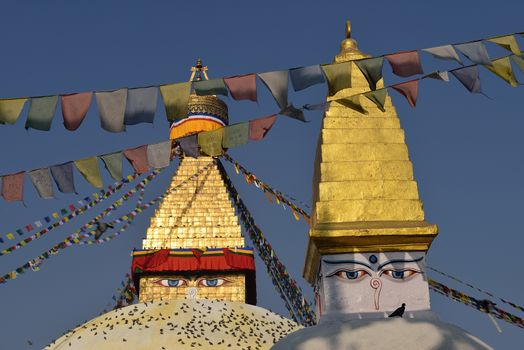 Boudhanath Stupa. Golden spire and all seeing Buddha eyes on top a giant white hemisphere. Smaller stupa in foreground. Kathmandu, Nepal