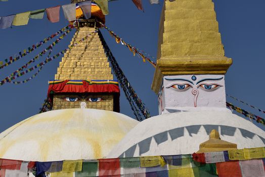 Boudhanath Stupa. Golden spire and all seeing Buddha eyes on top a giant white hemisphere. Smaller stupa in foreground. Kathmandu, Nepal