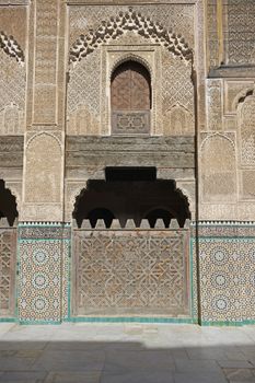 Ornate carving on the plastered walls and on the woodwork in the courtyard of the historic Madrasa Bou Inania in the ancient medina of Fes in Morocco