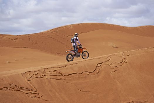 Person motorbiking across the sand dunes in the Sahara Desert of Morocco in North Africa