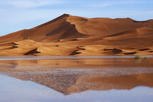 Sand dunes reflected in rainwater lakes in the Sahara Desert of Morocco in North Africa