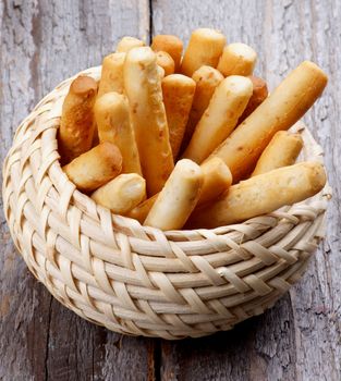 Bread Sticks with Sesame Seeds in Wicker Bowl isolated on Rustic Wooden background