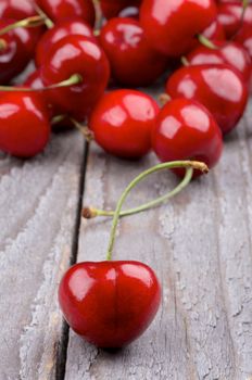 Sweet Cherry on Heap of Cherries closeup on Rustic Wooden background