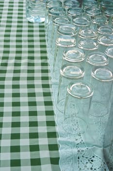 Empty glass upside down on a table covered by a green and white stripes.