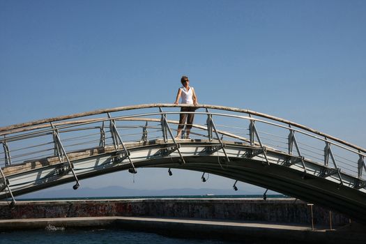 Lady on the bridge connecting two sides of sea breakwater