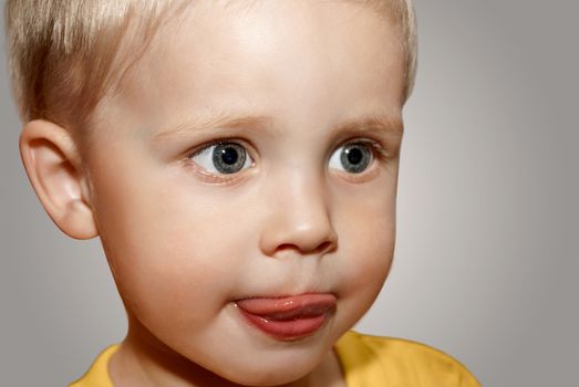 Face little boy on the gray background.