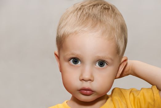 Face little boy on the gray background.