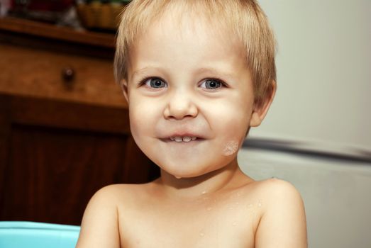 Little funny boy with a funny expression on his face washed in the bath.