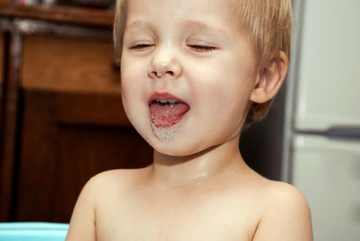 Little funny boy with a funny expression on his face washed in the bath.