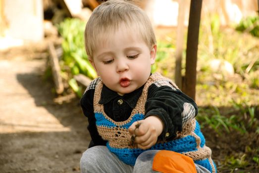 Little boy sitting in the garden playing ground.