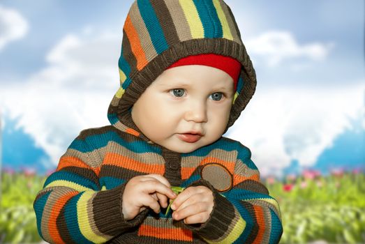 Little boy with leaf in hand knitted clothes outdoors.