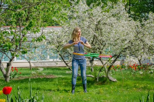 girl turning hula hoop between flowering cherry tree to have a perfect waist