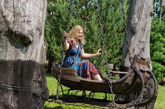 young blond woman swinging in ancient decorative swings antique wooden sleigh