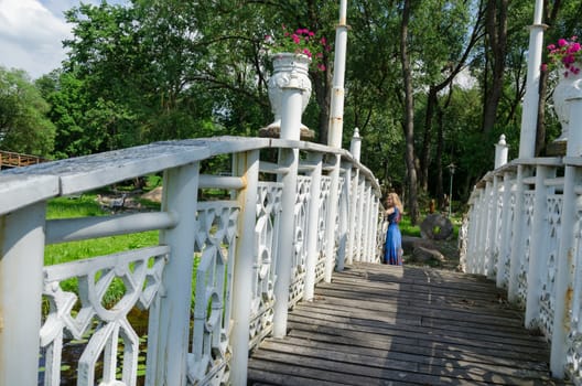 old wooden bridge with white wiggle railings and girl resting at the end of bridge