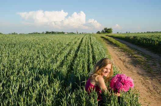 long village sand path and woman sitting with peony flower near rye field