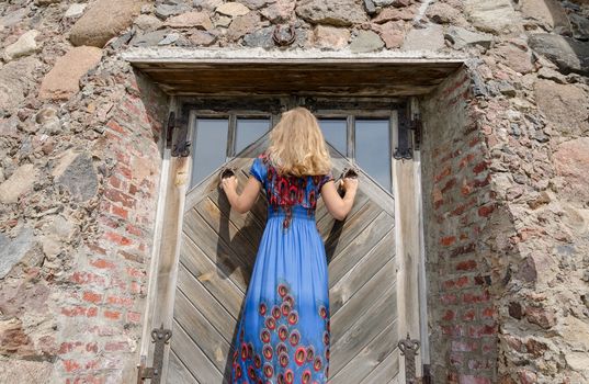back view of woman with long dress at the retro old manor door entrance