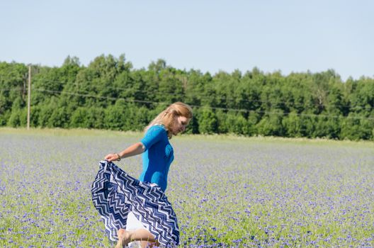 young girl dance in the endless cornflower meadow summer time