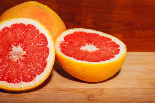 Slices of ripe red grapefruit on wooden board.