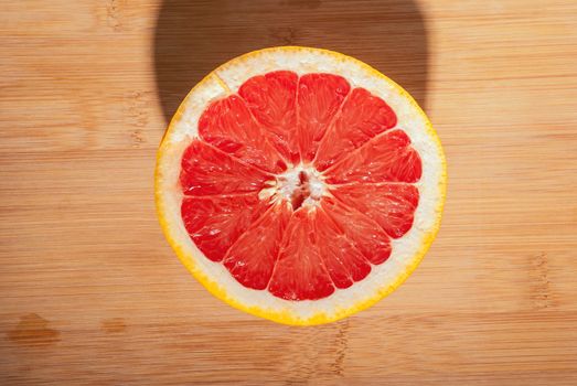 Slices of ripe red grapefruit on wooden board.